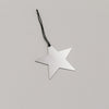 Schlichter silberner Sternanhänger aus Metall mit schwarzem Band, auf hellem Untergrund liegend.