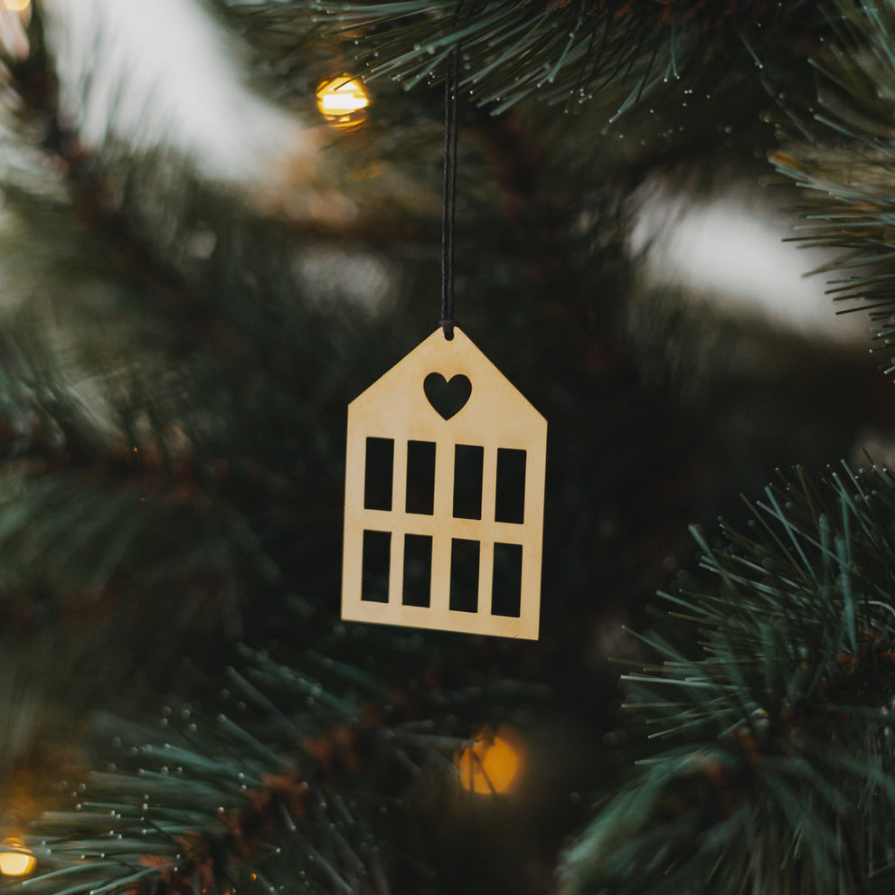 Goldener Hausanhänger  mit schwarzem Band an grünem Tannenzweig.