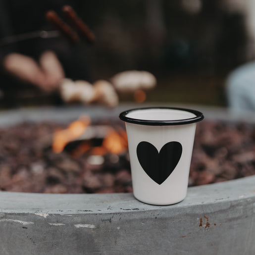 Emaille Tasse Herz in Off-White am Lagerfeuer – stilvoller Begleiter für Camping und Outdoor-Momente.
