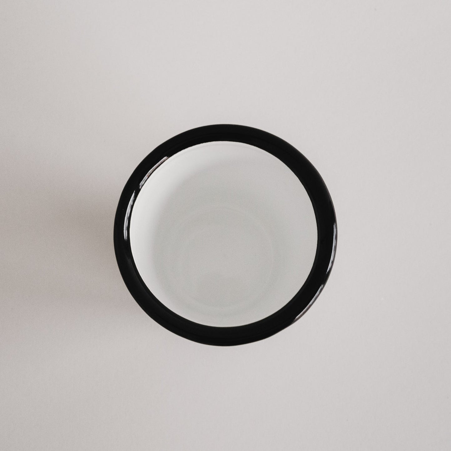 Emaille Tasse Herz von oben fotografiert – schlichtes Off-White Design mit schwarzem Rand.