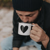 Person trinkt aus Emaille Tasse Herz – perfekter Begleiter für Kaffee oder Tee beim Camping.