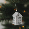 Weißer Metallanhänger in Hausform mit Herzdetail als festliche Weihnachtsdeko am Tannenbaum