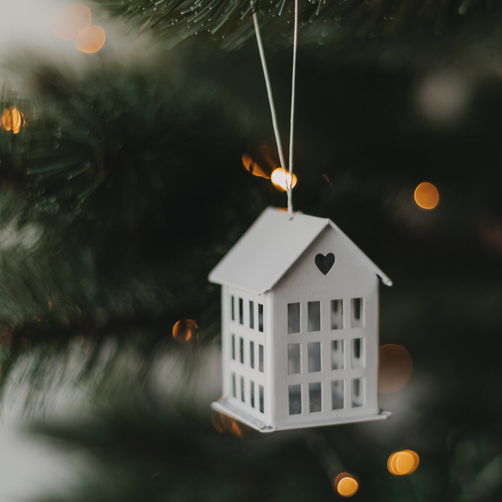 Weißer Metallanhänger in Hausform mit Herzdetail als festliche Weihnachtsdeko am Tannenbaum