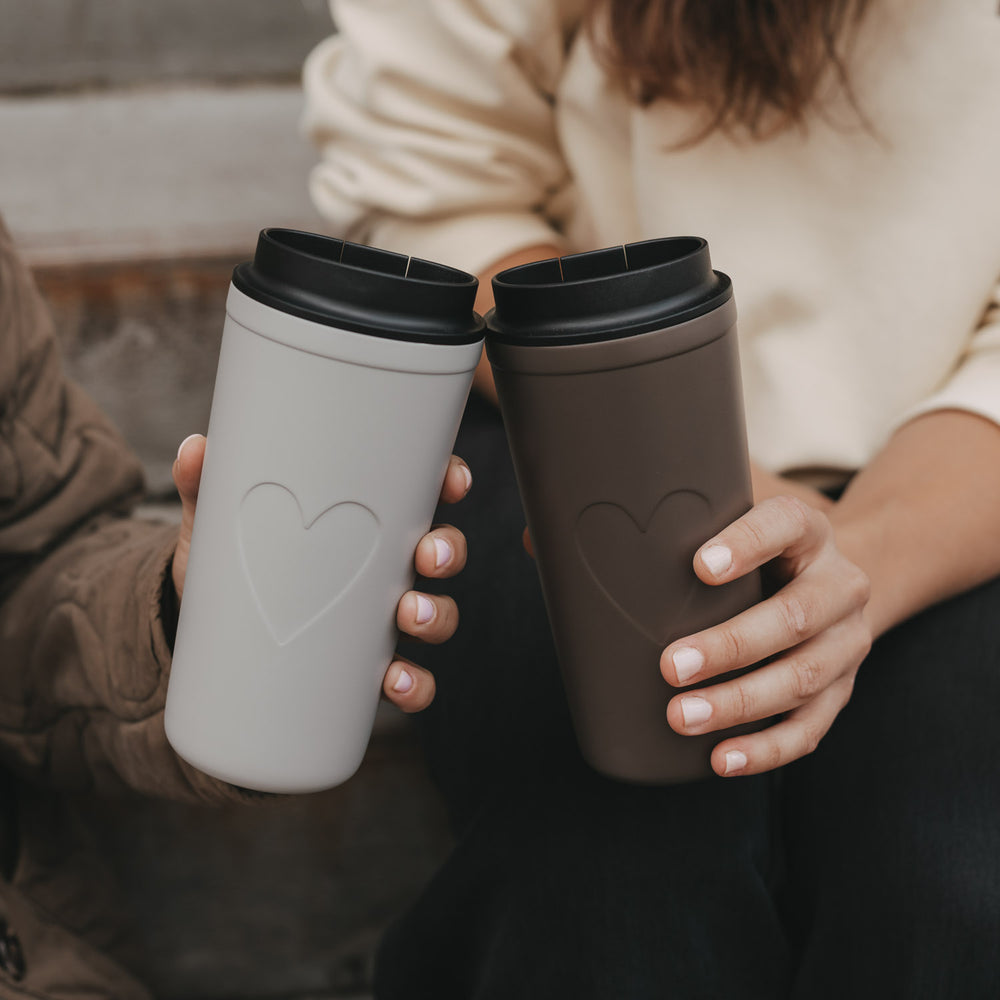 Grauer und brauner To-go-Thermobecher mit Herzmotiv und schwarzem Deckel