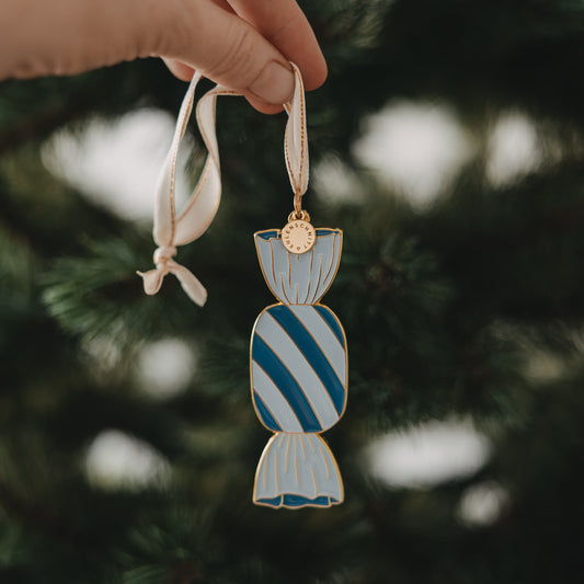 Hand hält Bonbon Christbaumschmuck blau-weiß, festliche Weihnachtsdeko am Baum