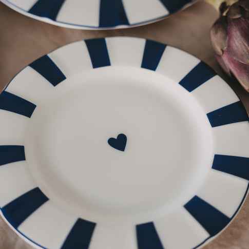 Detailaufnahme Frühstücksteller aus Porzellan mit gewelltem Rand, dunkelblauen Streifen und kleinem Herz