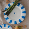 Speiseteller aus Porzellan mit gewelltem Rand, hellblauen Streifen und Herzdetail, dekoriert mit grünem Spargel