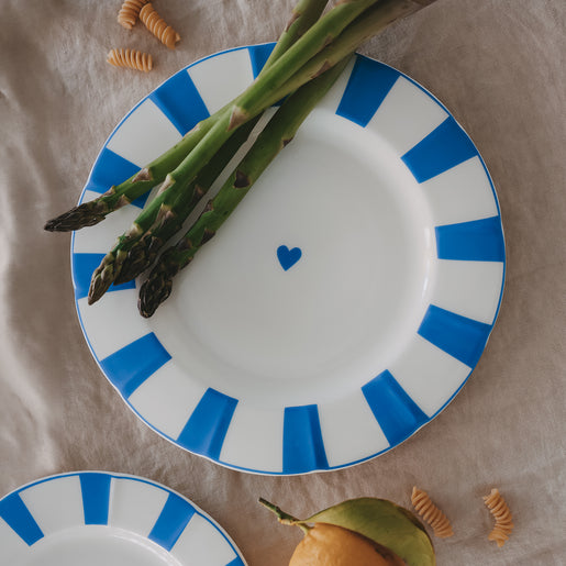 Speiseteller aus Porzellan mit gewelltem Rand, hellblauen Streifen und Herzdetail, dekoriert mit grünem Spargel