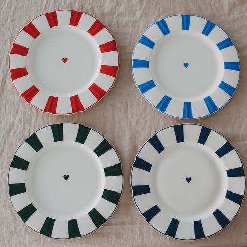 4 Porzellanteller mit gewelltem Rand, Streifenmuster und Herzdetail in verschiedenen Farben Rot, Dunkelblau, Hellblau und Grün, übersichtlich angeordnet