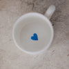 Draufsicht in die Tasse – innen ein kleines hellblaues Herz am Boden.