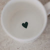 Innenansicht einer weißen Tasse mit kleinem grünem Herz am Boden