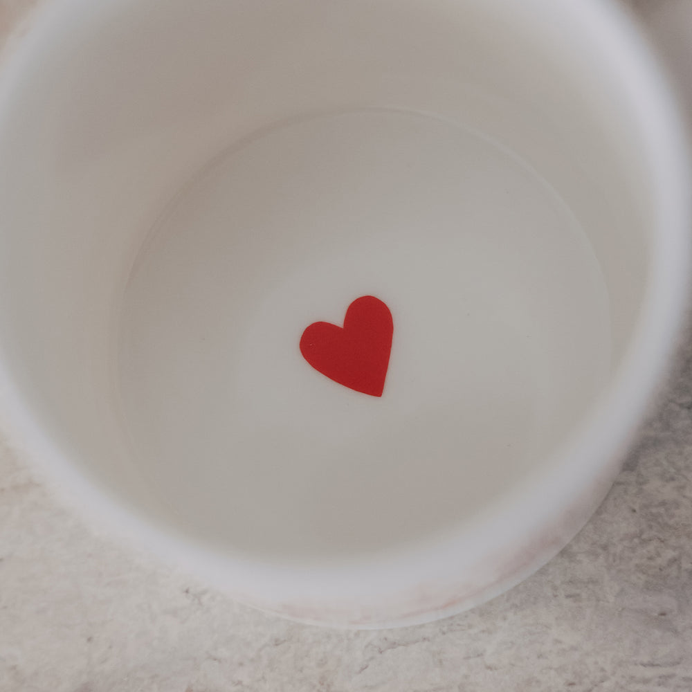 Draufsicht in eine weiße Tasse mit kleinem rotem Herz auf dem Tassenboden