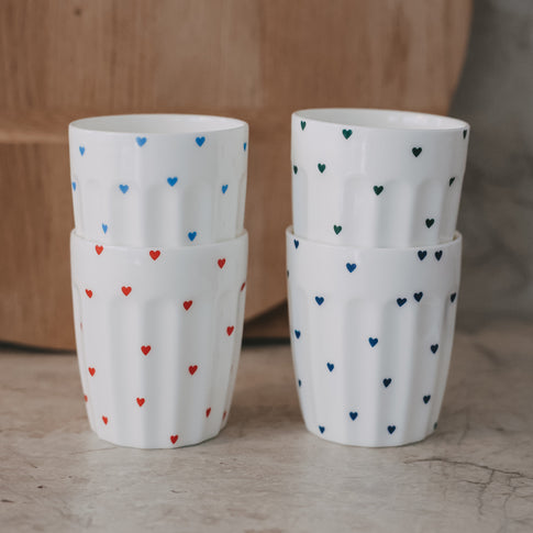 Stapelbarer Keramikbecher mit bunten Herzmotiven in Blau, Rot und Grün, dekorativ und modern