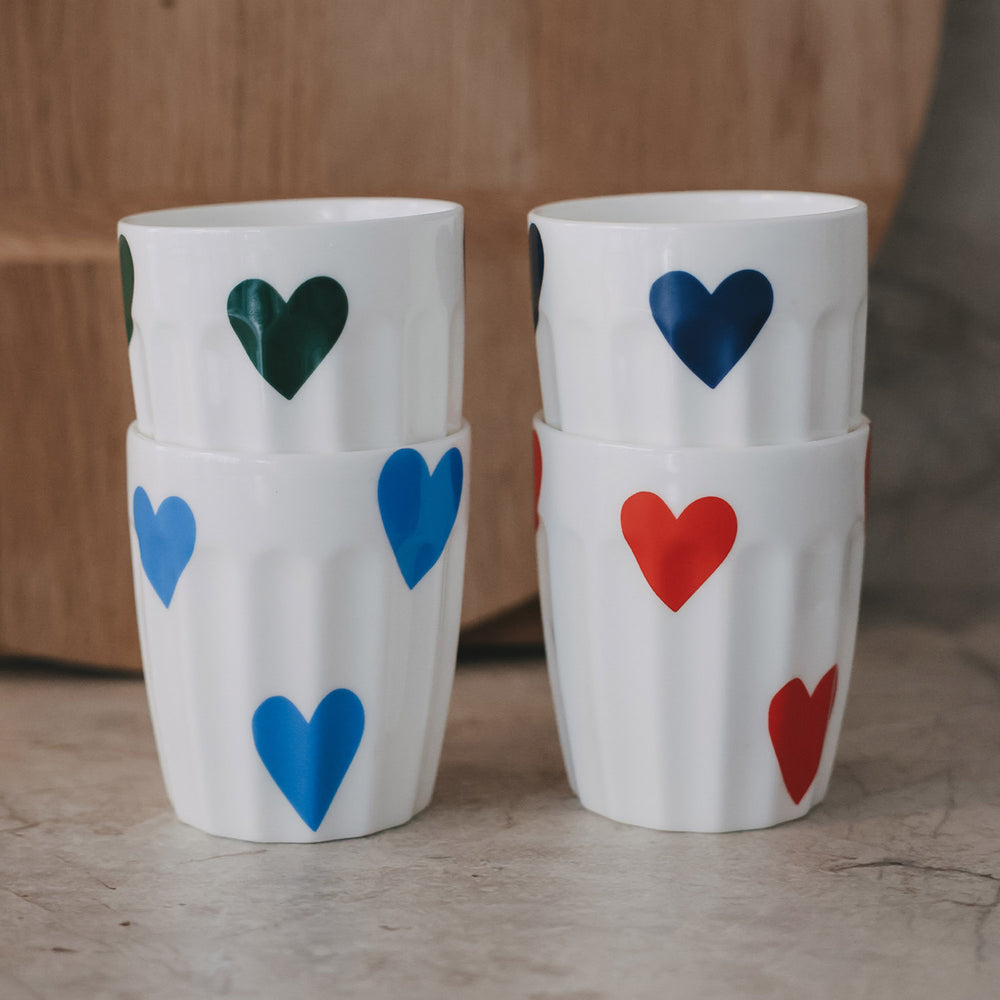 Vier gestapelte Keramikbecher mit großen Herzmotiven in Blau, Grün und Rot