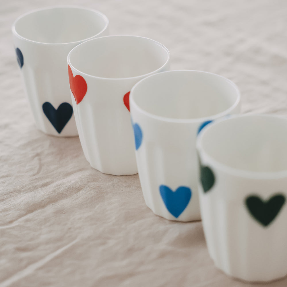 Keramikbecher mit Herzmotiven in Reihe auf Stoffuntergrund, modernes Design