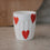 Weißer Keramikbecher mit roten Herzmotiven, modernes schlichtes Design