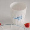 Keramikbecher „breakfast club“ in Blau neben Erdbeeren, modernes Frühstücks-Setup