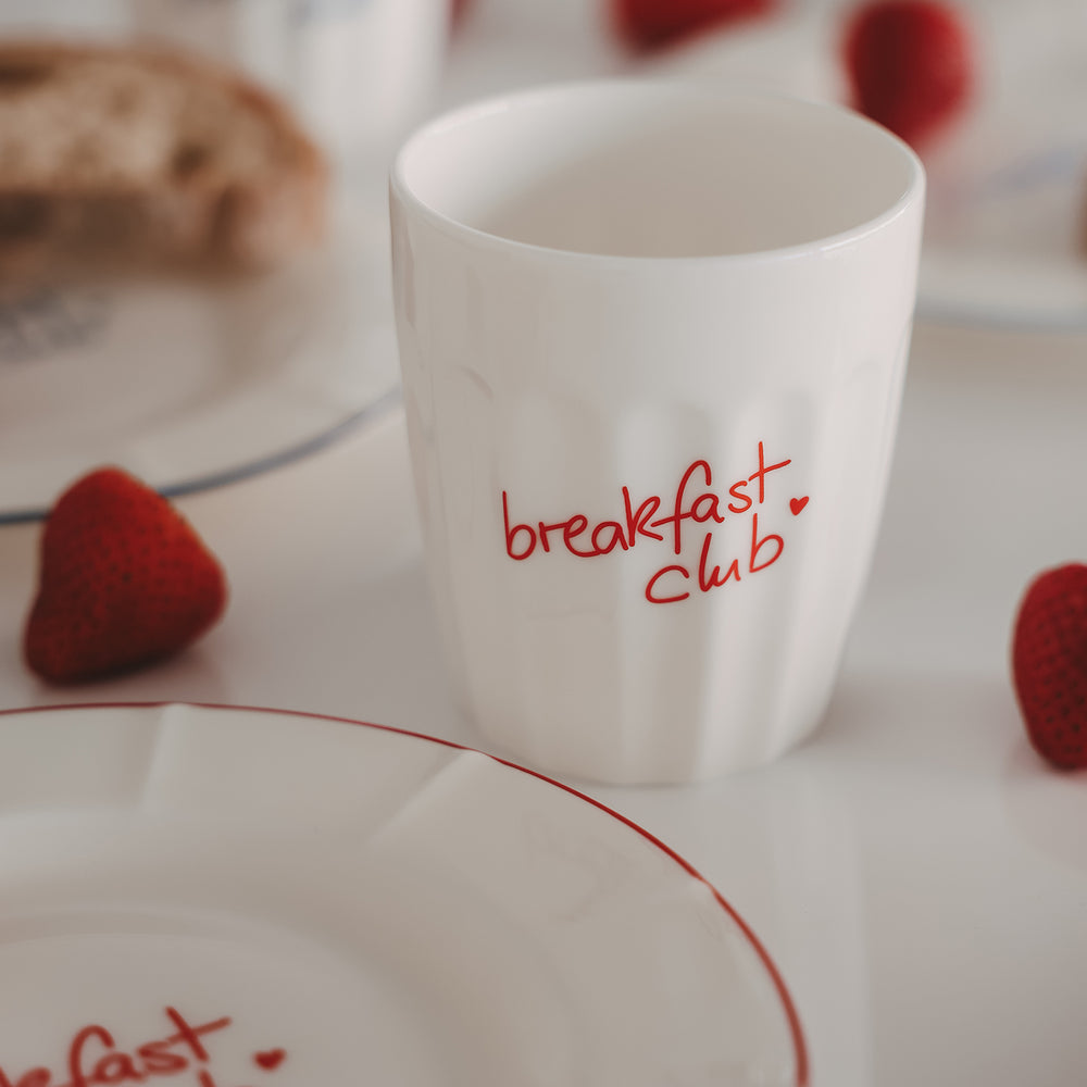 Keramikbecher „breakfast club“ mit rotem Schriftzug neben Teller und Erdbeeren, Frühstücksszene