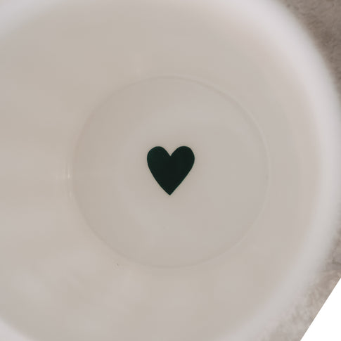 Detailansicht Becherboden mit grünem Herz im Inneren eines weißen Keramikbechers