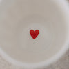 Detailansicht Becherboden mit rotem Herz im Inneren eines weißen Keramikbechers