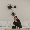 Schwarze Papiersterne mit Lichterkette als minimalistische Weihnachtsdeko über weißem Sofa