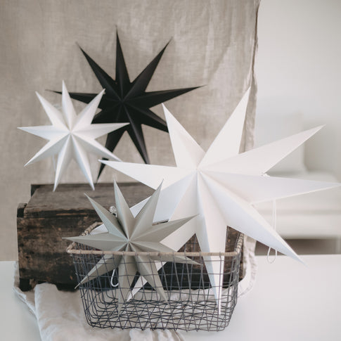 Papiersterne in Schwarz, Weiß und Grau in einem Korb – minimalistische Weihnachtsdeko im skandinavischen Stil.