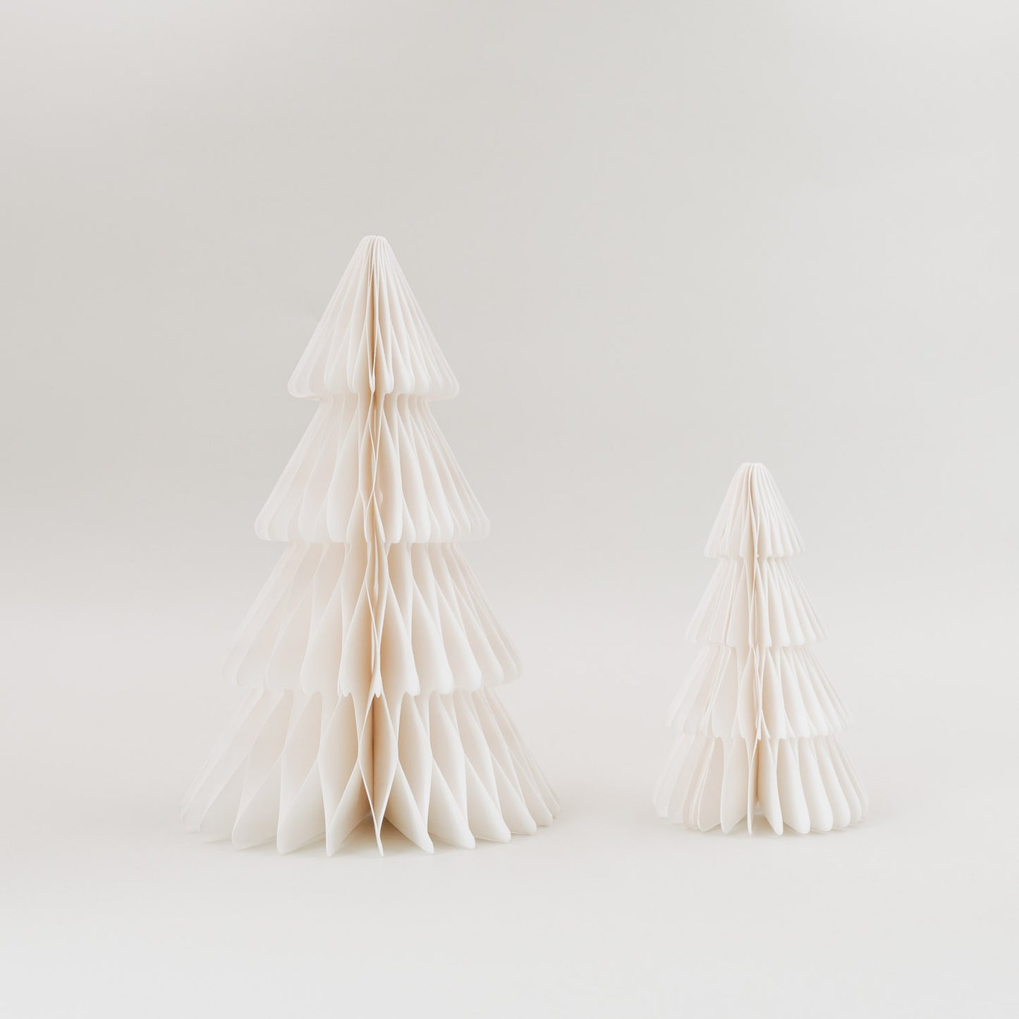 Zwei naturweiße Papiertannen im 2er Set in Wabenoptik als nachhaltige Weihnachtsdeko vor hellem Hintergrund