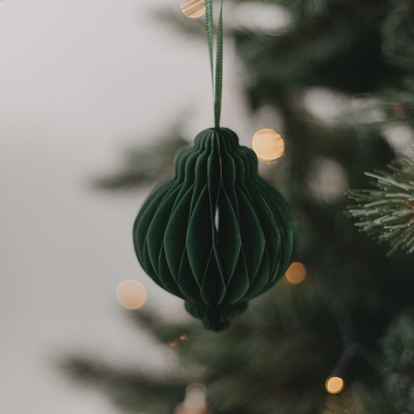 Hängender Papieranhänger in Dunkelgrün am Weihnachtsbaum – eleganter Blickfang im Weihnachtsgrün.