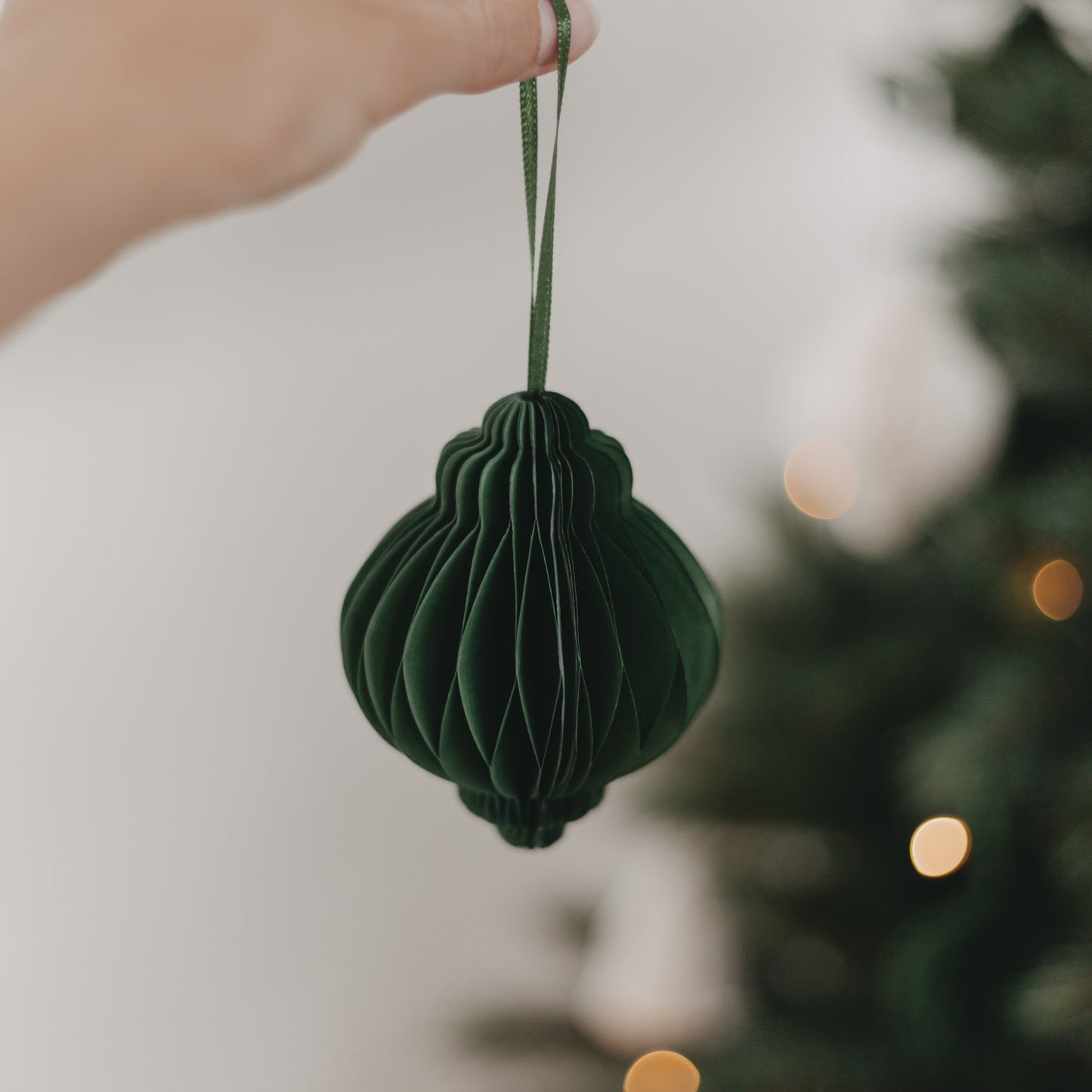 Papieranhänger in Dunkelgrün vor Weihnachtsbaum – festliche Baumdeko mit stilvollem Charakter.
