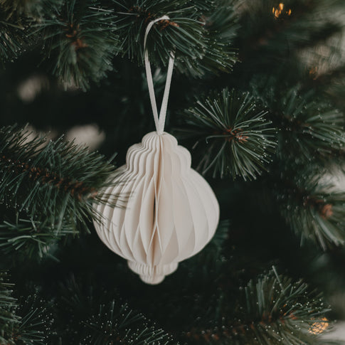 Detailansicht eines Papieranhängers in Naturfarbe am grünen Weihnachtsbaum, elegant und schlicht