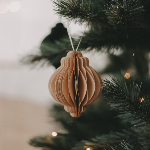 Wabenförmiger Papieranhänger in warmem Braunton als elegante Deko am grünen Weihnachtsbaum.