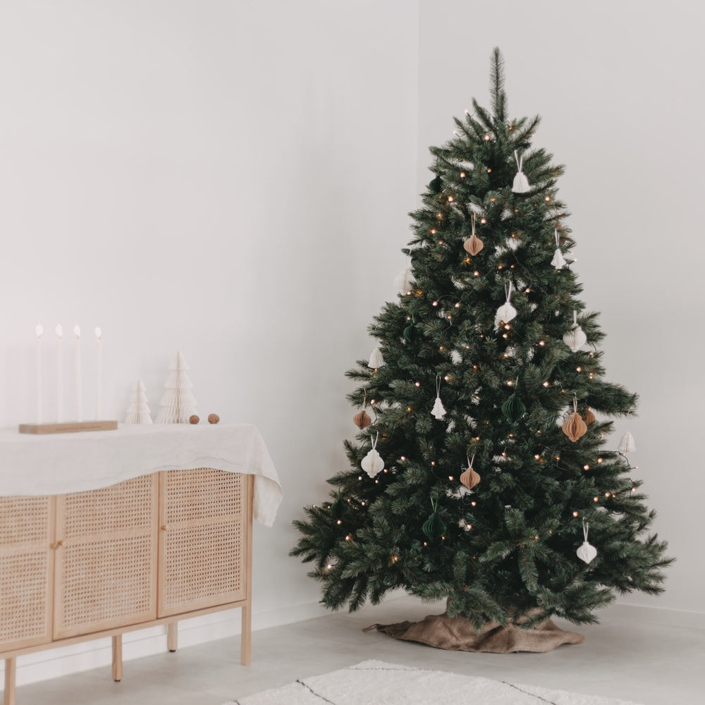 Geschmückter Weihnachtsbaum mit Papieranhängern in Dunkelgrün, Braun und Weiß in modernem, skandinavischem Interieur.