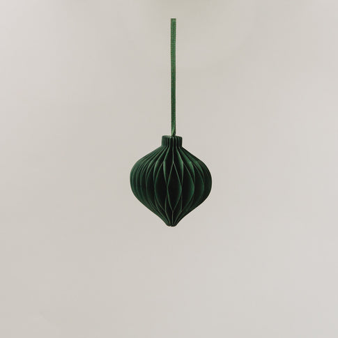 Ein dunkelgrüner Papieranhänger in voller Wabenoptik hängt an einem Band vor hellem Hintergrund.