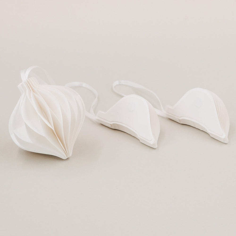 Weißer Papieranhänger geöffnet und zwei zusammengefaltete Anhänger mit Magnetverschluss im Vordergrund