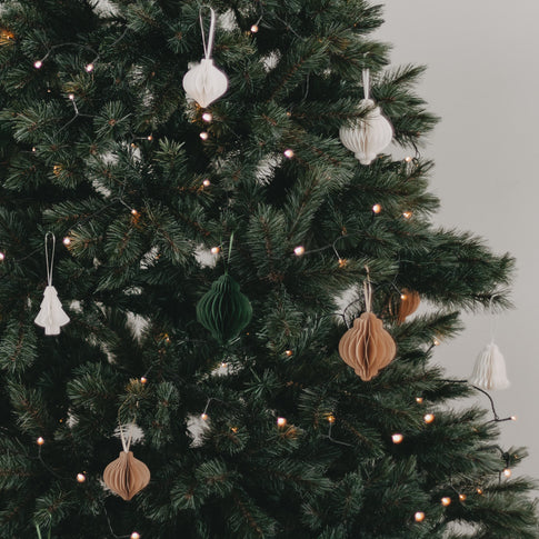 Geschmückter Weihnachtsbaum mit braunen, weißen und grünen Papieranhängern.