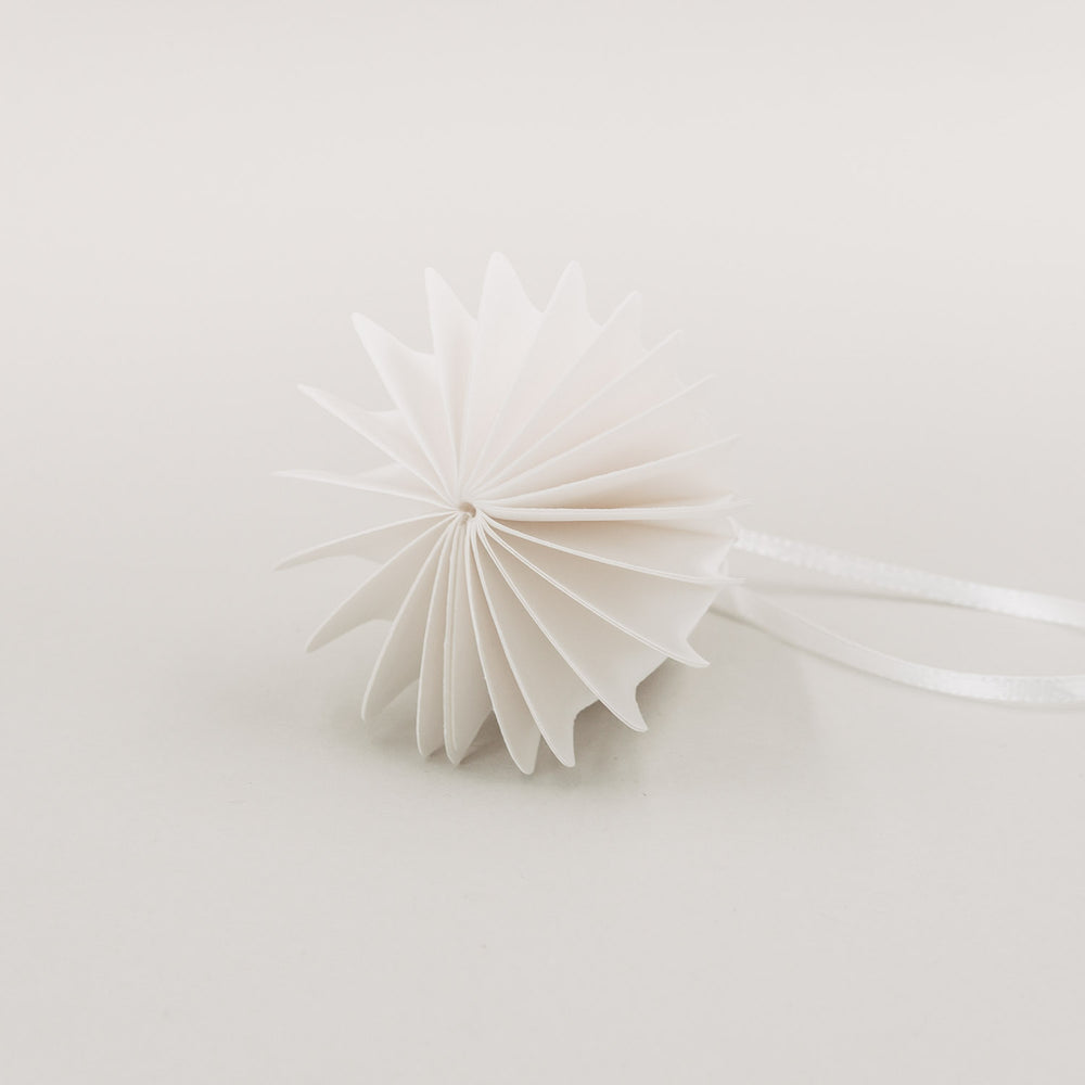 Weiße Papierglocke in Draufsicht zeigt elegante Wabenstruktur und feine Faltung mit Schleifenband.