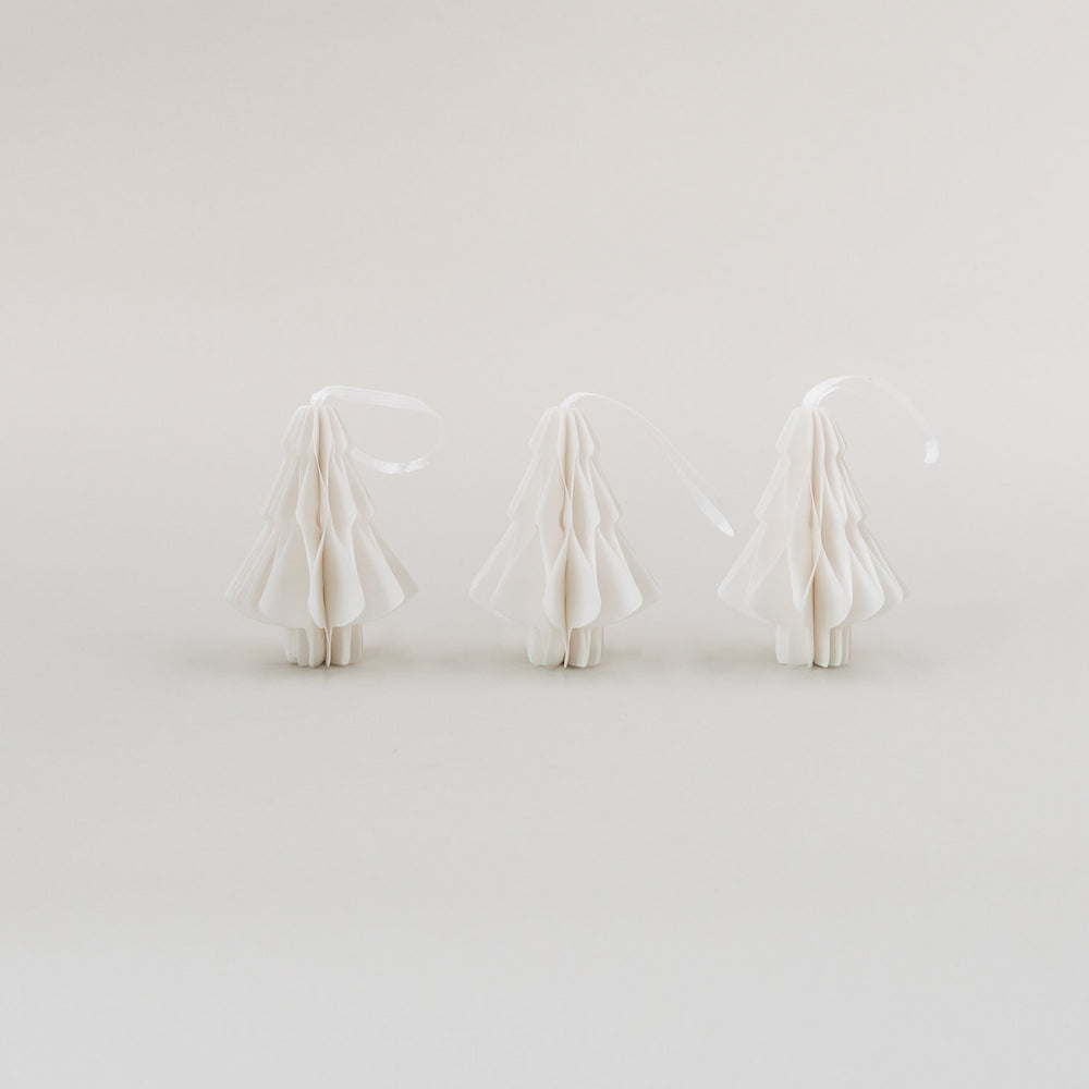 Drei weiße Papieranhänger in Tannenform mit Wabenoptik, aufrecht nebeneinander stehend auf hellem Hintergrund.