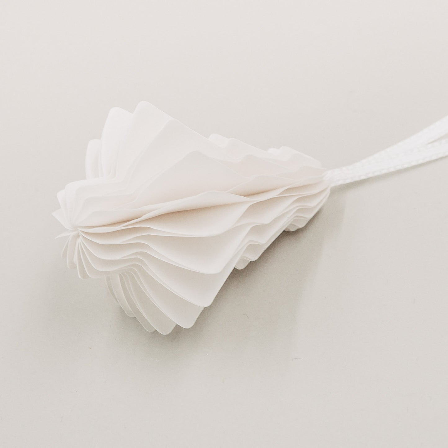 Detailansicht eines zusammengefalteten Papieranhängers Tanne mit feiner Wabenstruktur und weißem Band.