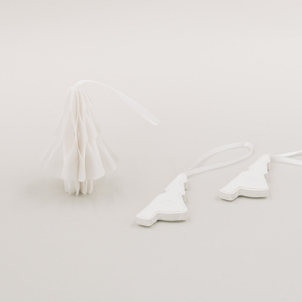 Ein aufgefalteter Tannenanhänger und zwei zusammengelegte Anhänger nebeneinander liegend.