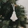 Weißer Papieranhänger in Tannenform am Weihnachtsbaum mit Lichterkette