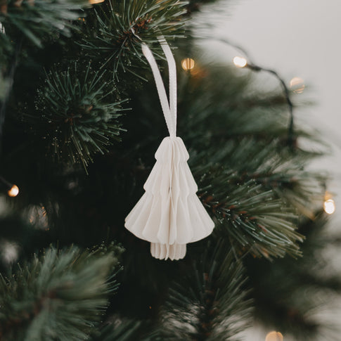 Weißer Papieranhänger in Tannenform am Weihnachtsbaum mit Lichterkette