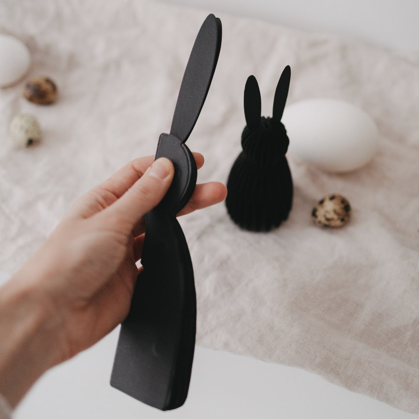 Hand hält schwarzen Papierhasen aus dem 2er-Set, detailreiche Nahaufnahme.