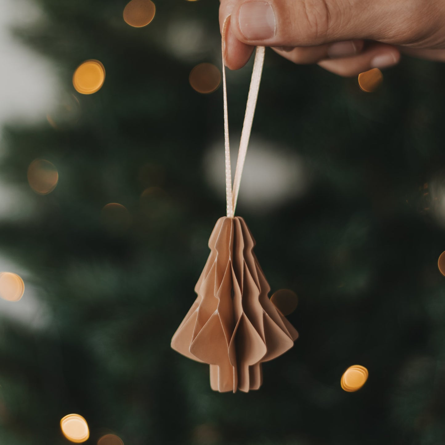 Brauner Papierbaum als Christbaumschmuck wird an den Weihnachtsbaum gehängt