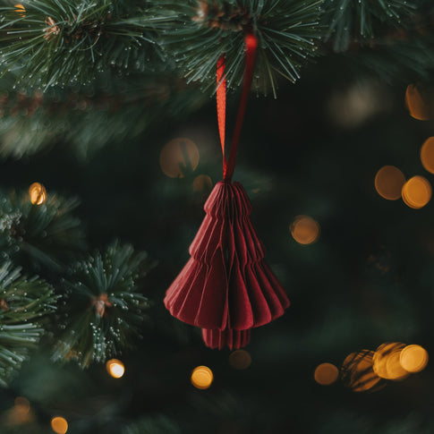 Rote Papiertanne als Christbaumschmuck am Weihnachtsbaum mit rotem Band