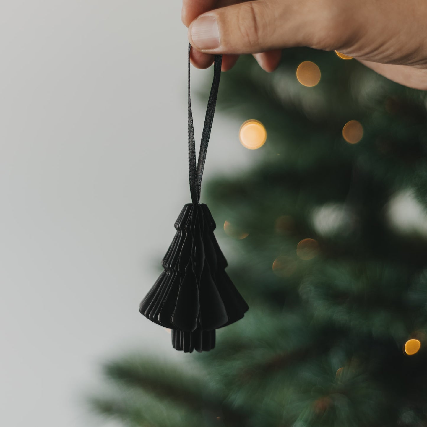 Schwarze Papiertanne als Christbaumschmuck wird in der Hand gehalten