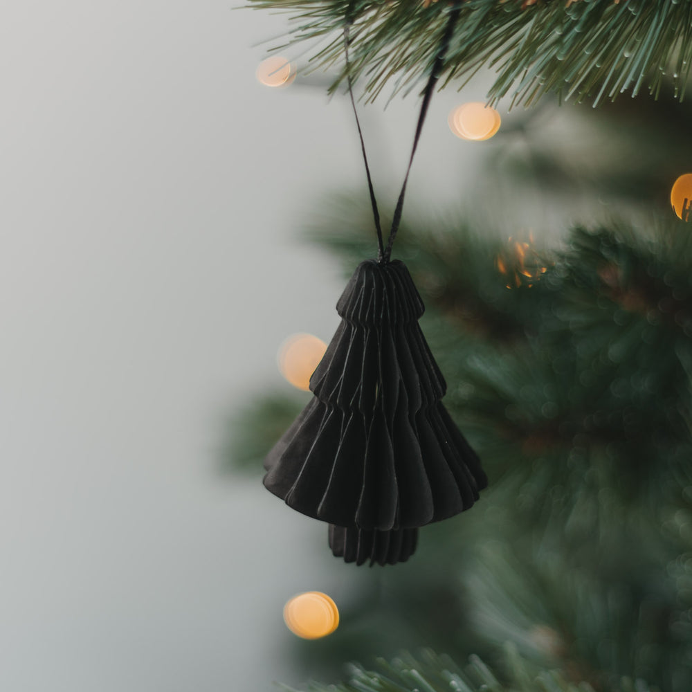 Schwarze Papiertanne als Weihnachtsanhänger am Tannenzweig