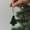 Grüne Papiertanne als Christbaumschmuck wird an den Weihnachtsbaum gehängt