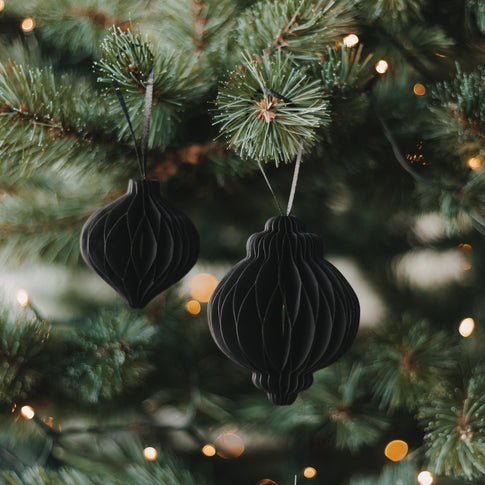 Zwei schwarze Papieranhänger in Kugelform als moderner Christbaumschmuck am Weihnachtsbaum