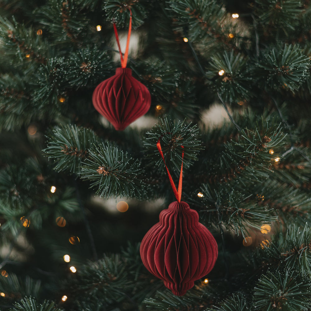 Zwei rote Papieranhänger in Kugelform als festlicher Christbaumschmuck am Weihnachtsbaum