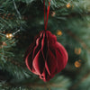 Roter Papieranhänger in Kugelform am Weihnachtsbaum mit warm leuchtender Lichterkette